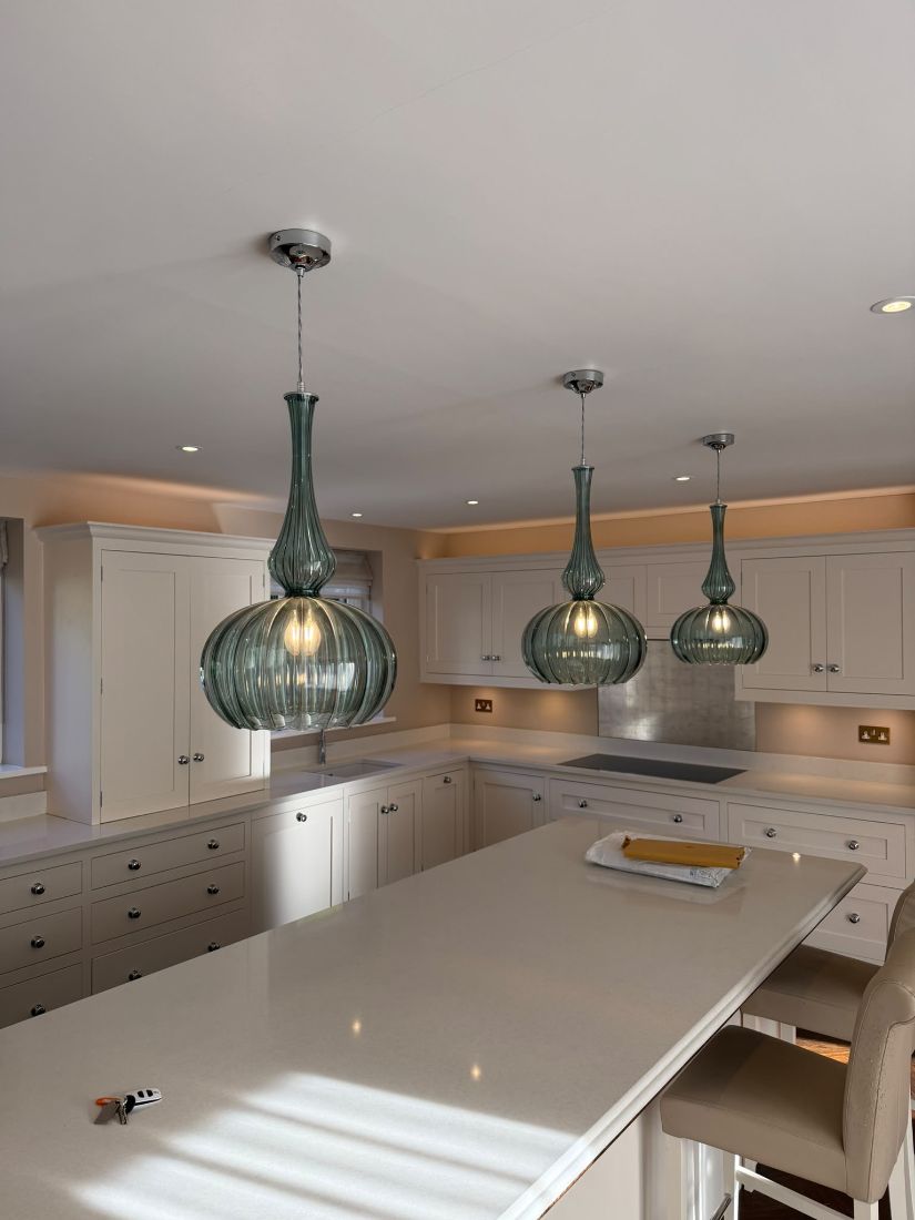 Pendant lights over a kitchen island with downlights and under-cabinet LEDs